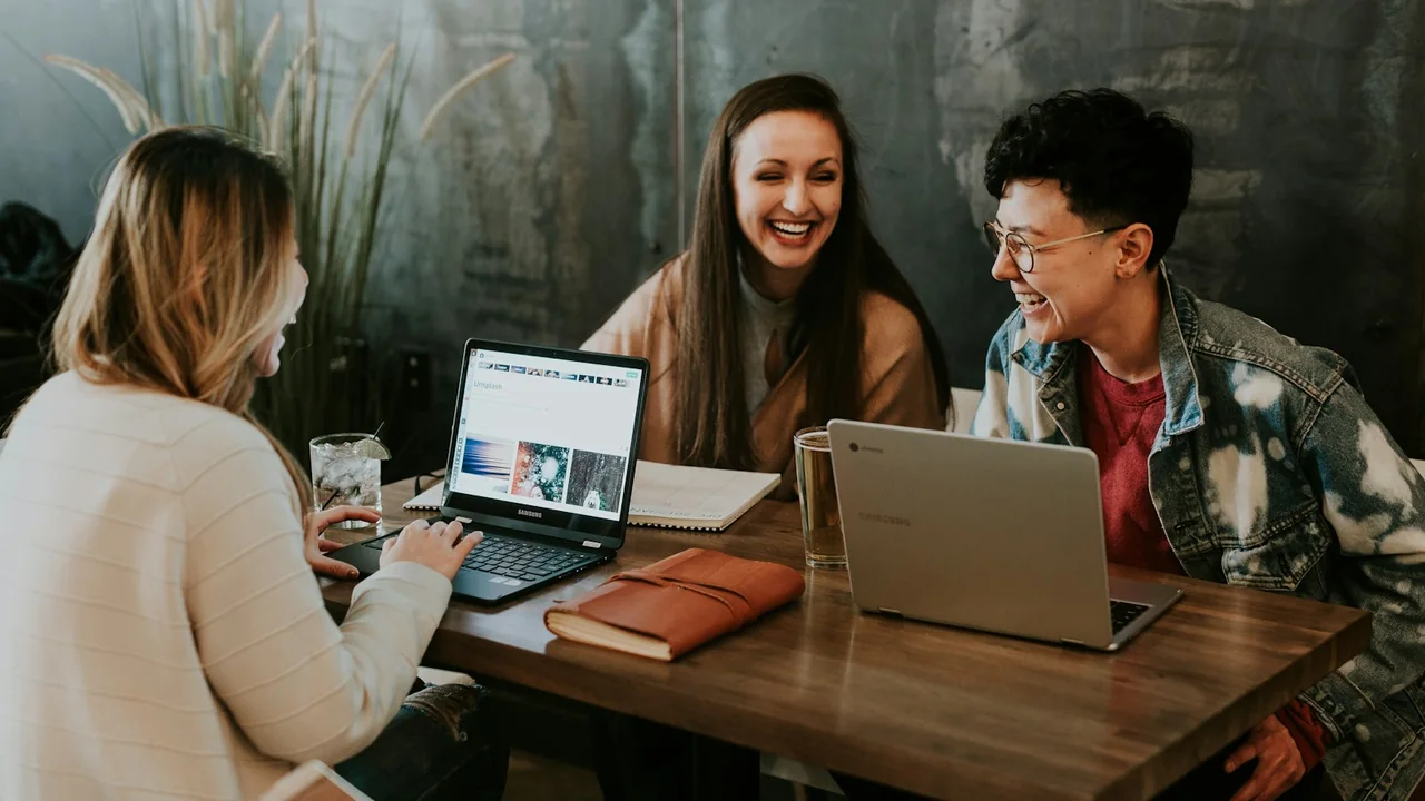 Estudantes analisam uma atividade em grupo com cadernos e computadores