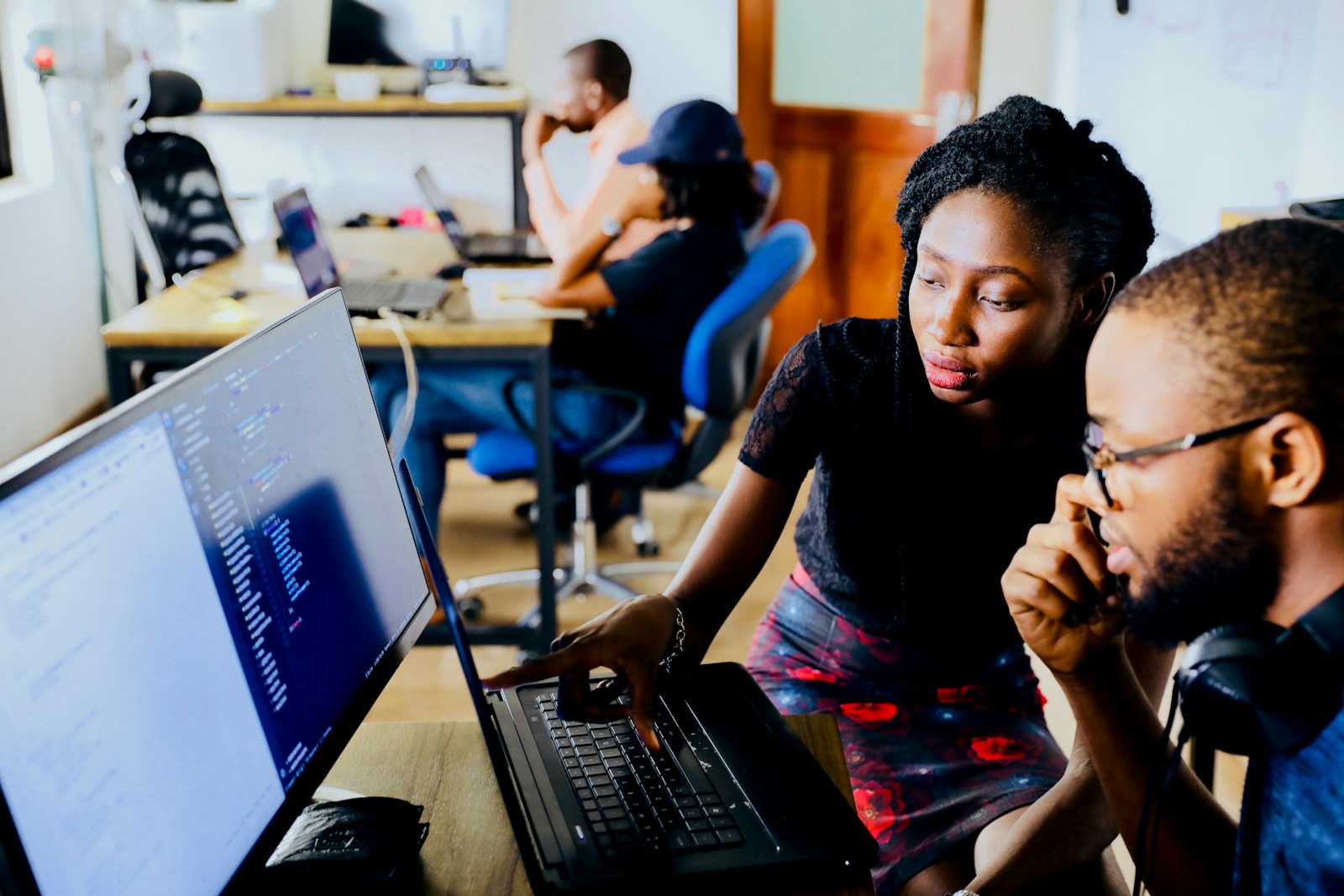 Duas pessoas trabalham juntas diante de laptops em uma sala de tecnologia; fonte e crédito: Unsplash, foto 1531482615713-2afd69097998.