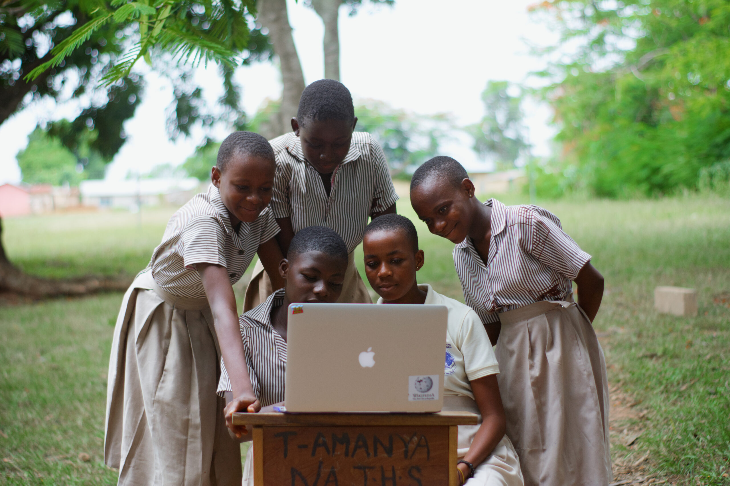 Estudantes consultam um laptop em uma escola; foto de Bright Kwame Ayisi (Wikimedia Commons, CC0).