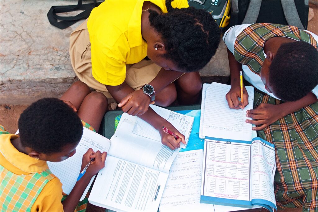 Pessoa estudando e escrevendo em uma mesa com materiais de aprendizagem — foto de Kwameghana, Wikimedia Commons, CC0.