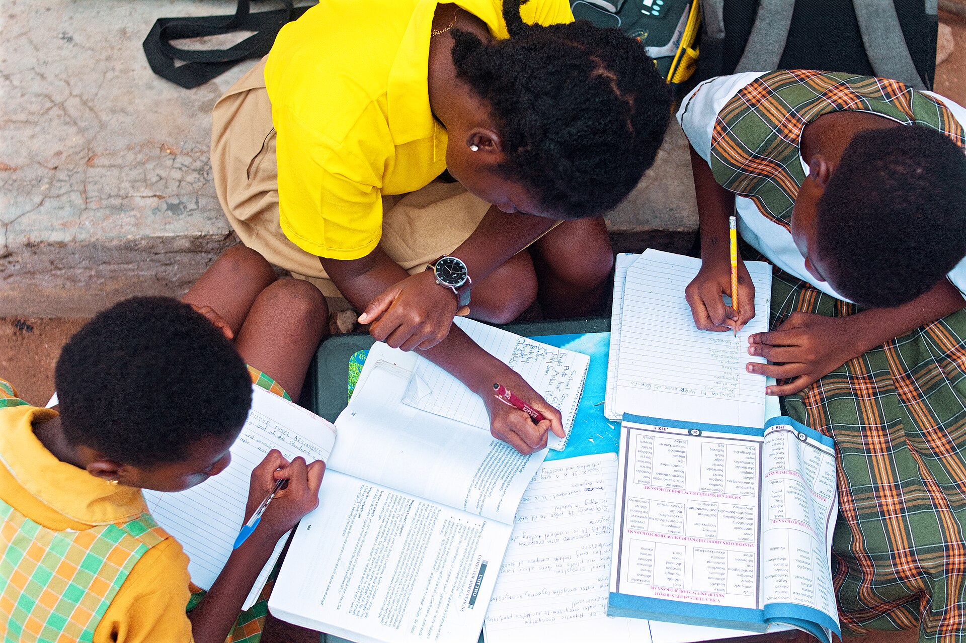 Pessoa estudando e escrevendo em uma mesa com materiais de aprendizagem — foto de Kwameghana, Wikimedia Commons, CC0.