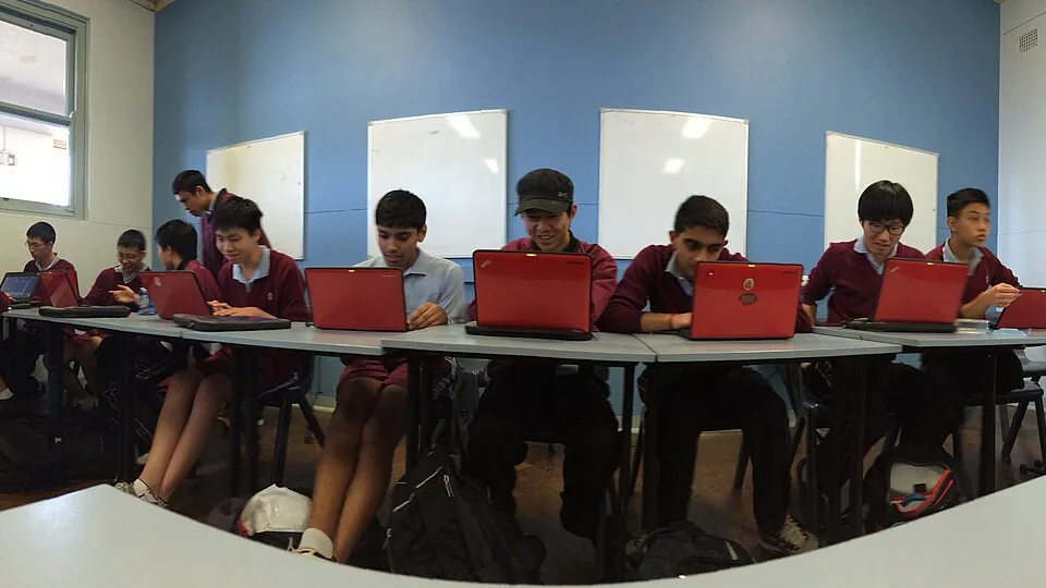 Estudantes participam de atividade colaborativa com computadores em sala de aula