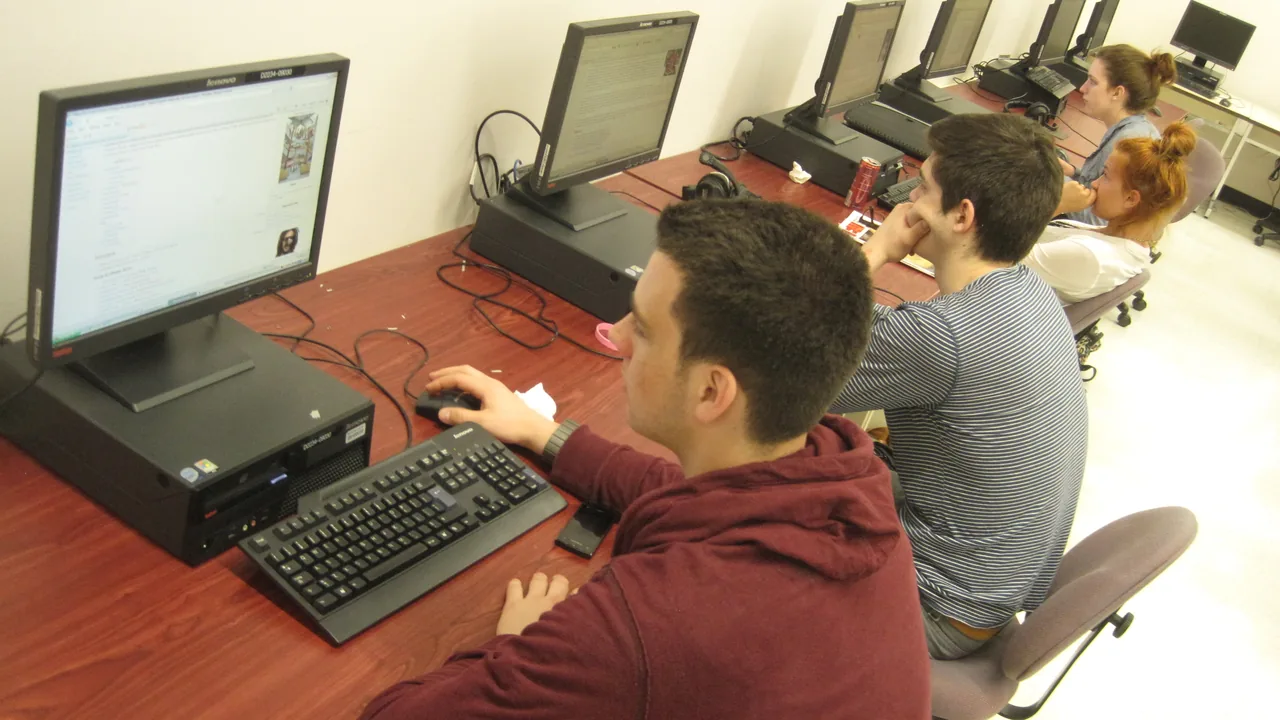 Estudantes trabalham em computadores durante uma atividade em laboratório