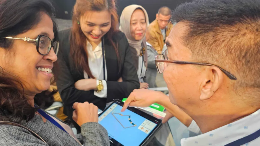Professores e estudantes observam uma simulação PhET em um tablet durante uma atividade de Ciências.