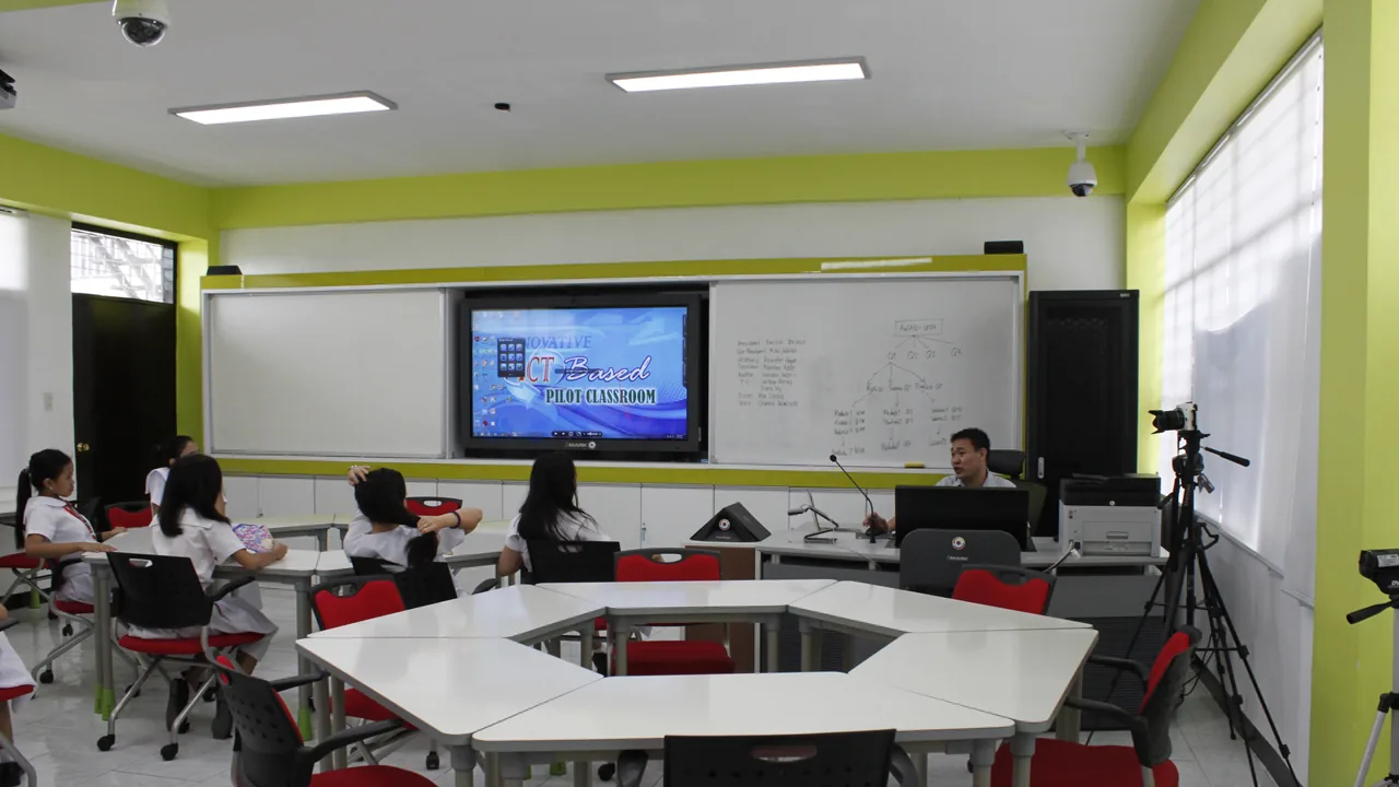 Professor e estudantes analisam informações em uma sala de aula equipada com tela e quadro