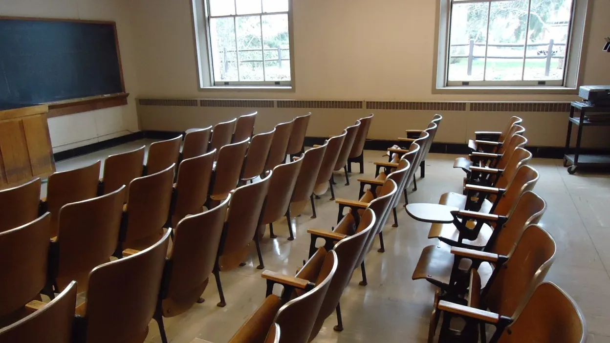 Sala de aula vazia com quadro e cadeiras organizadas para uma aula