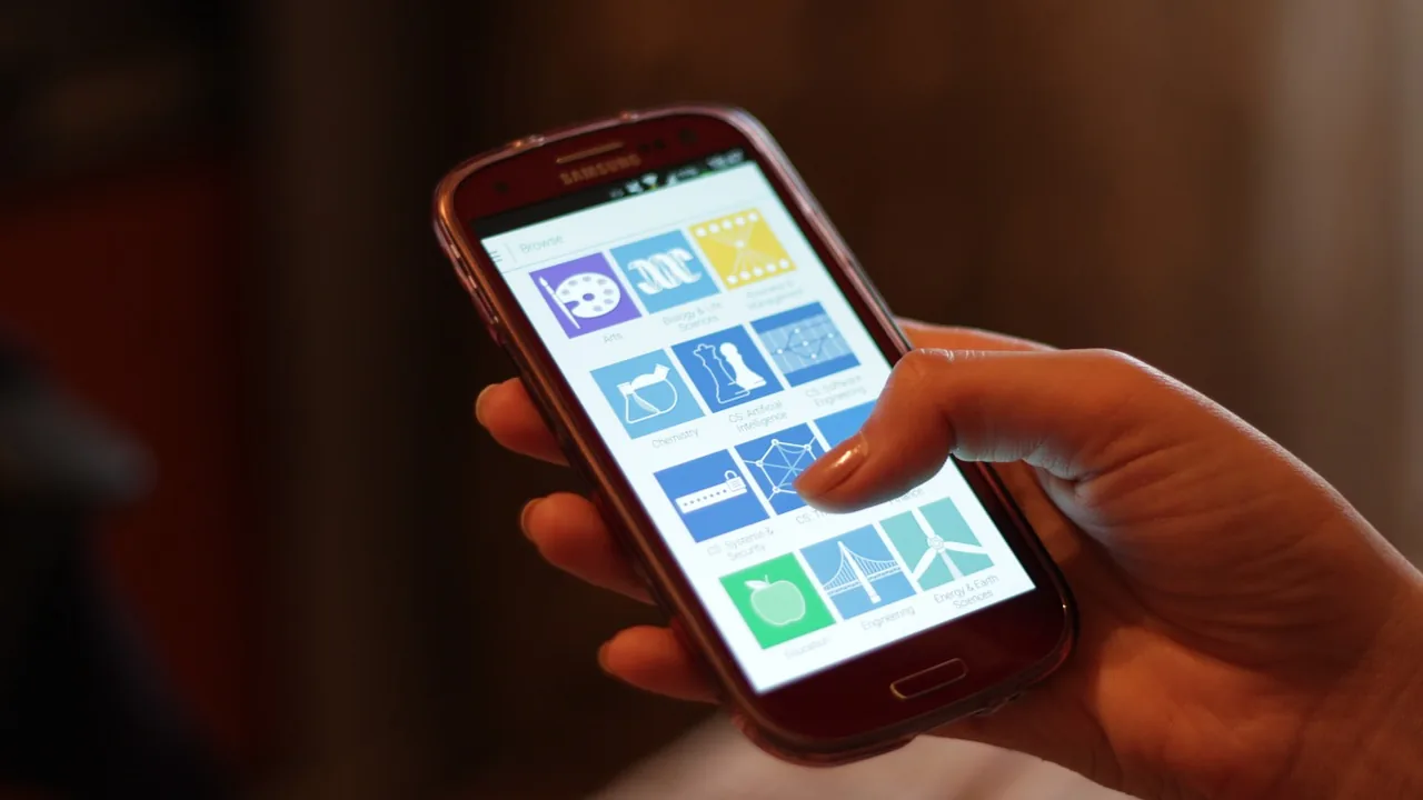 Mão segurando um smartphone com uma tela de aplicativos e conteúdos organizados em blocos
