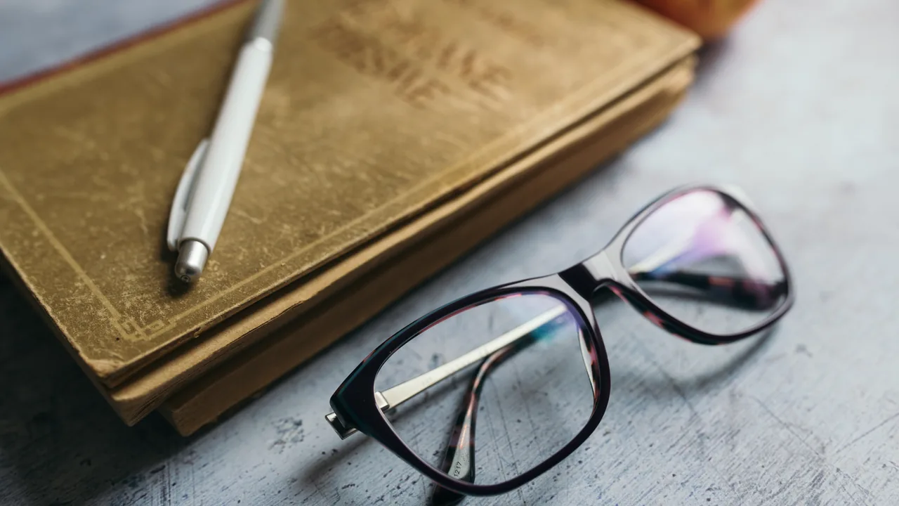 Cadernos, caneta e óculos sobre uma mesa de estudo